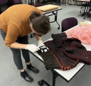 Acadia Roher performs conservation treatment of knitted sweater from the Ola Belle Reed collection. Photo by Laurainne Ojo-Ohikuare.